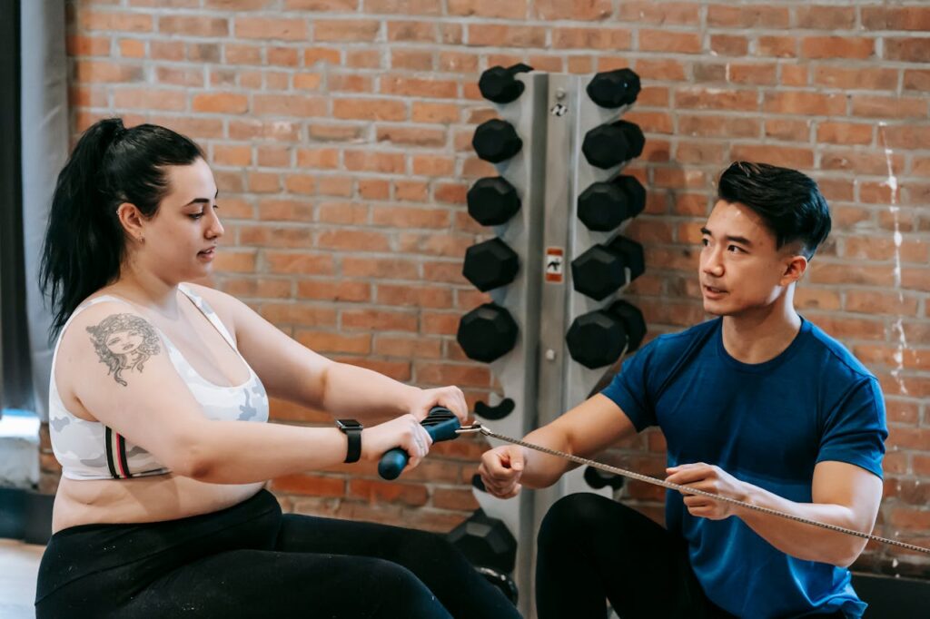 A-personal-trainer-next-to-a-woman-exercising-on-rowing-machine