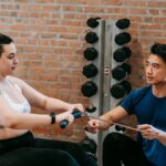 A-personal-trainer-next-to-a-woman-exercising-on-rowing-machine
