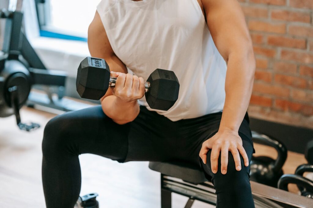 Crop-man-doing-weightlifting-exercise-on-bench