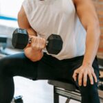 Crop-man-doing-weightlifting-exercise-on-bench