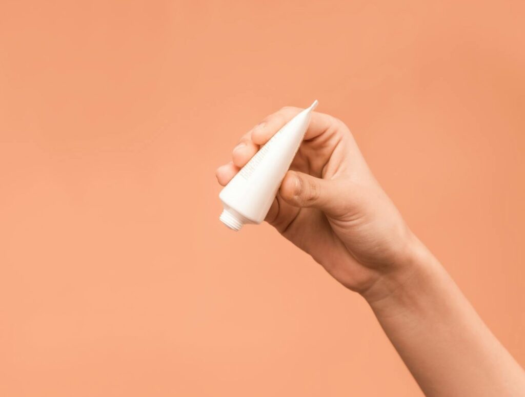 Person-Holding-White-Plastic-Tube