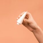 Person-Holding-White-Plastic-Tube