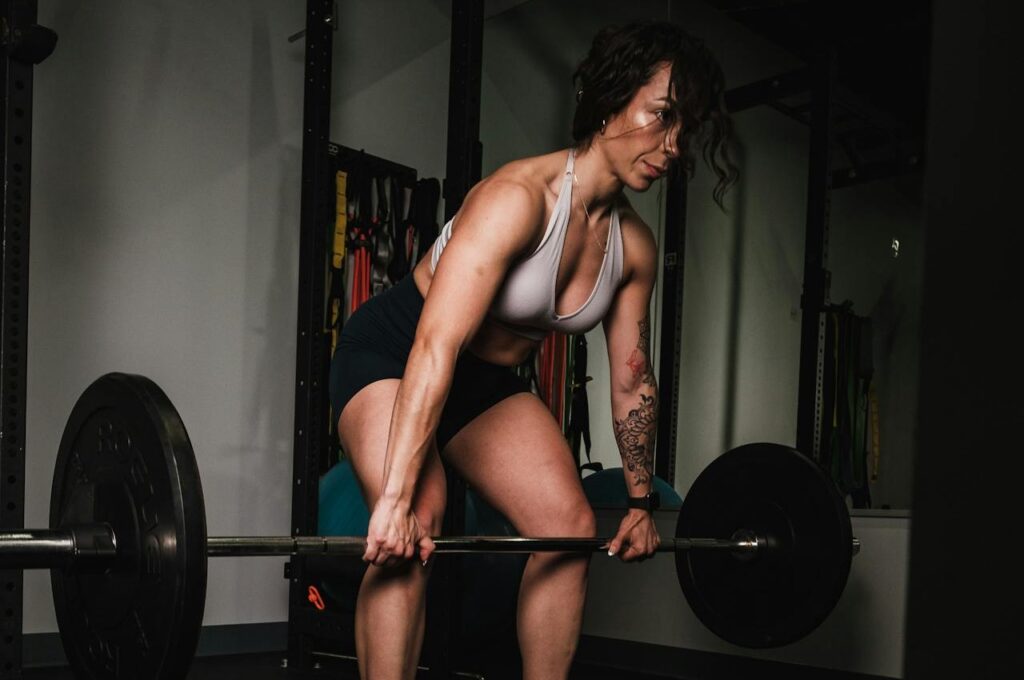 Woman-Leaning-on-Black-Barbell-in-Front-Mirror