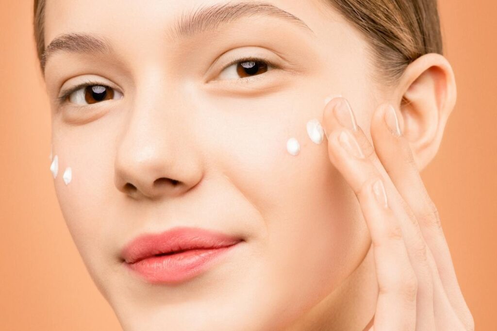 Woman-With-Pink-Lipstick-Applying-Facial-Cream