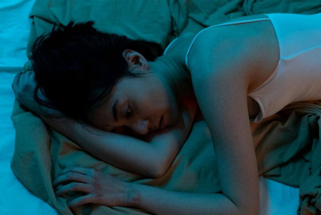 A-Woman-in-White-Tank-Top-Lying-on-Bed