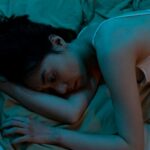 A-Woman-in-White-Tank-Top-Lying-on-Bed