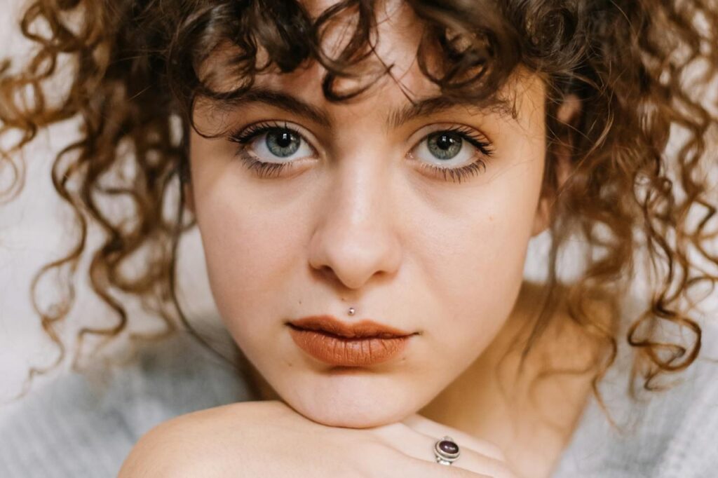 Close-Up-Shot-of-a-Curly-Haired-Woman-Looking-at-Camera