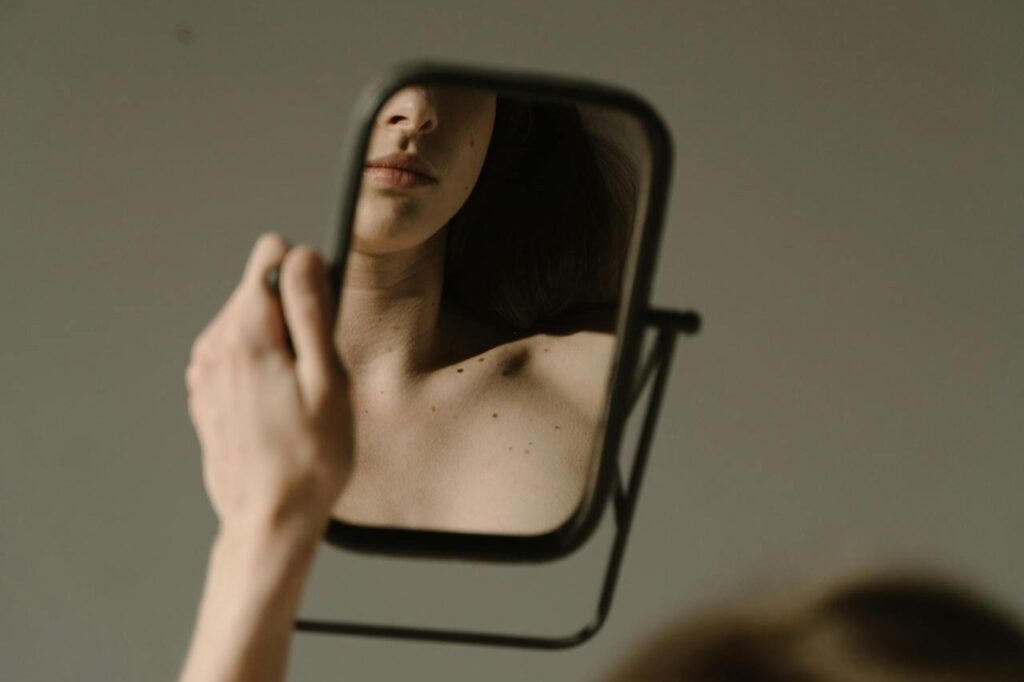 Woman-Sitting-on-a-Sofa-Looking-at-her-Reflection-on-a-Mirror