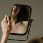 Woman-Sitting-on-a-Sofa-Looking-at-her-Reflection-on-a-Mirror