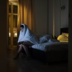 Woman-Sitting-on-the-Bed-while-Covered-by-a-White-Blanket