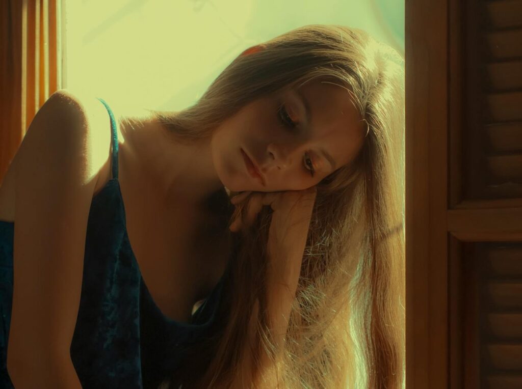Woman-in-Blue-Sleeveless-Dress-Sitting-on-Window